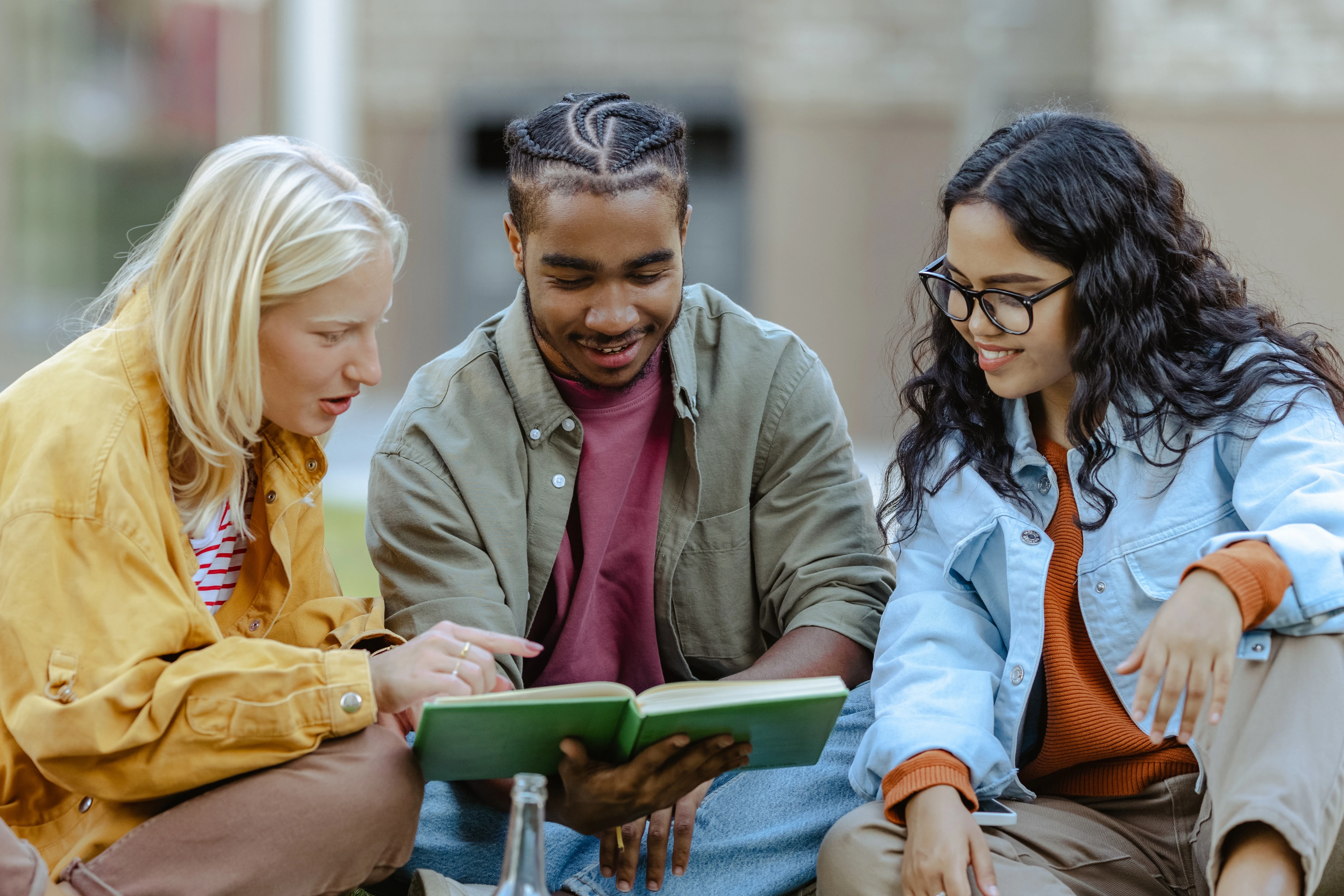 Students sitting outside on grass, studying together