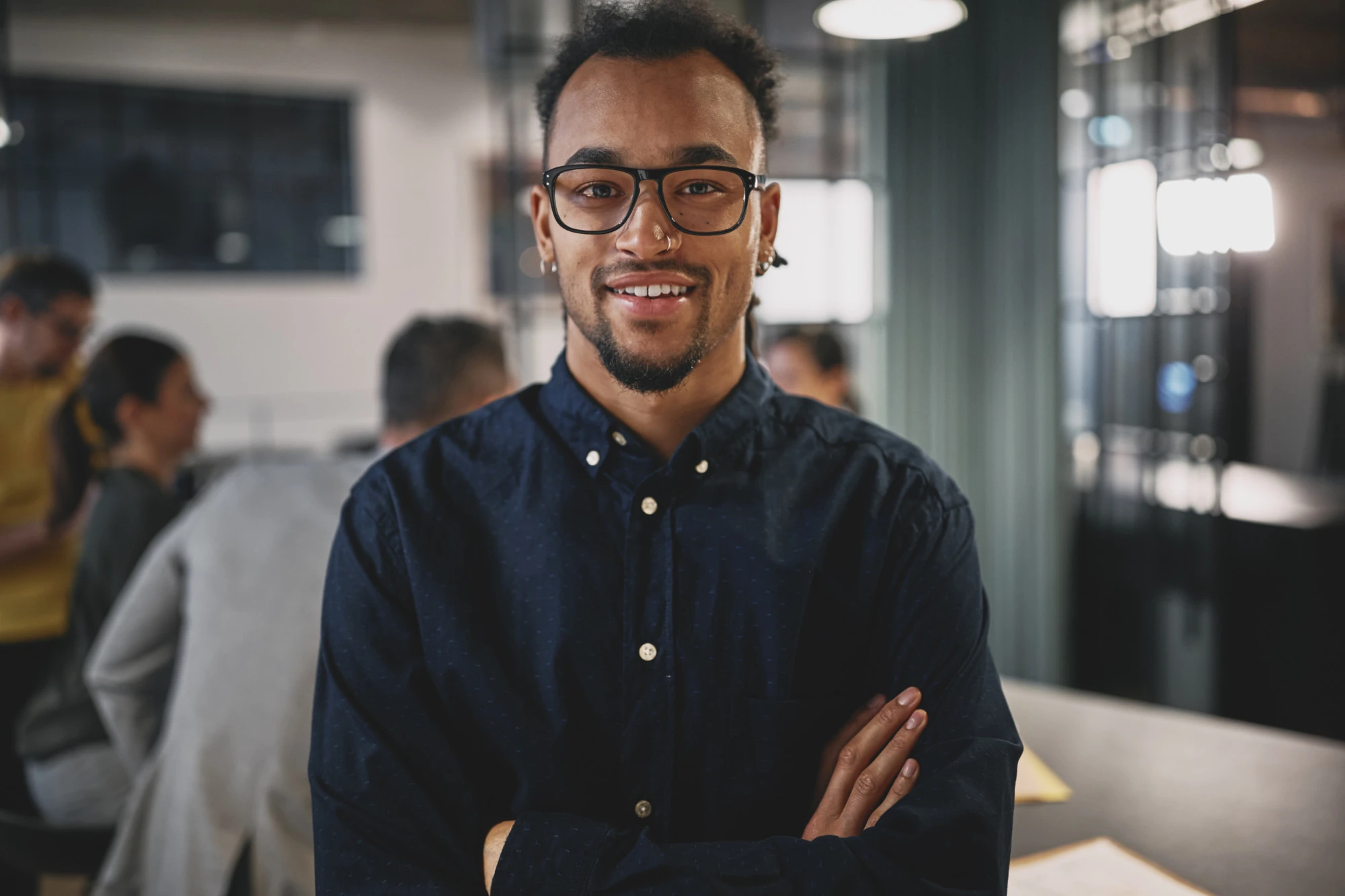 guy with glasses and folded arms in office environment