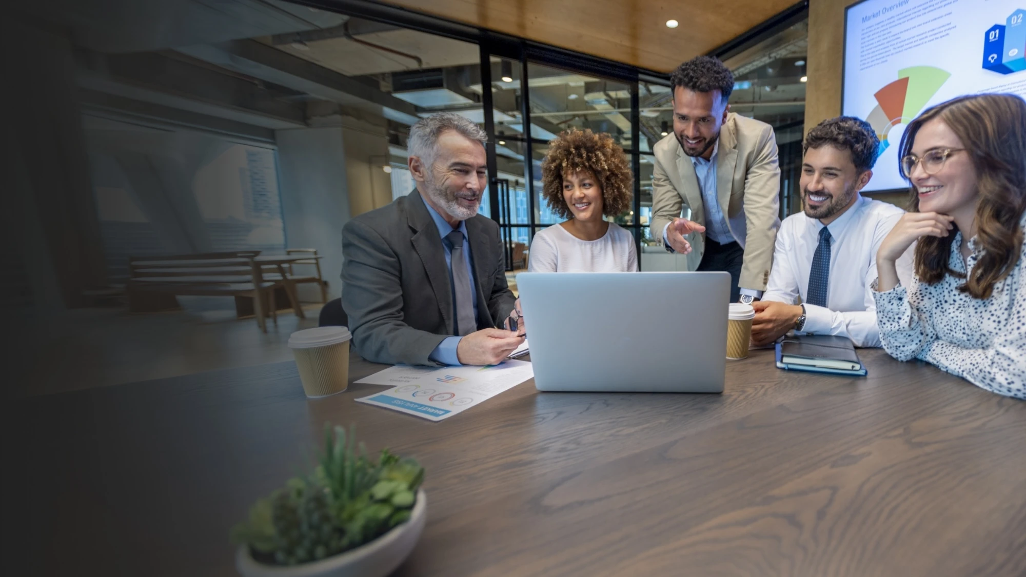 A group of colleagues sitting at a conference table looking at a laptop