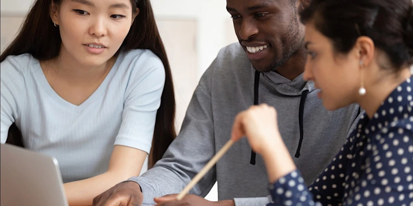 Three college students sitting and looking at a computer