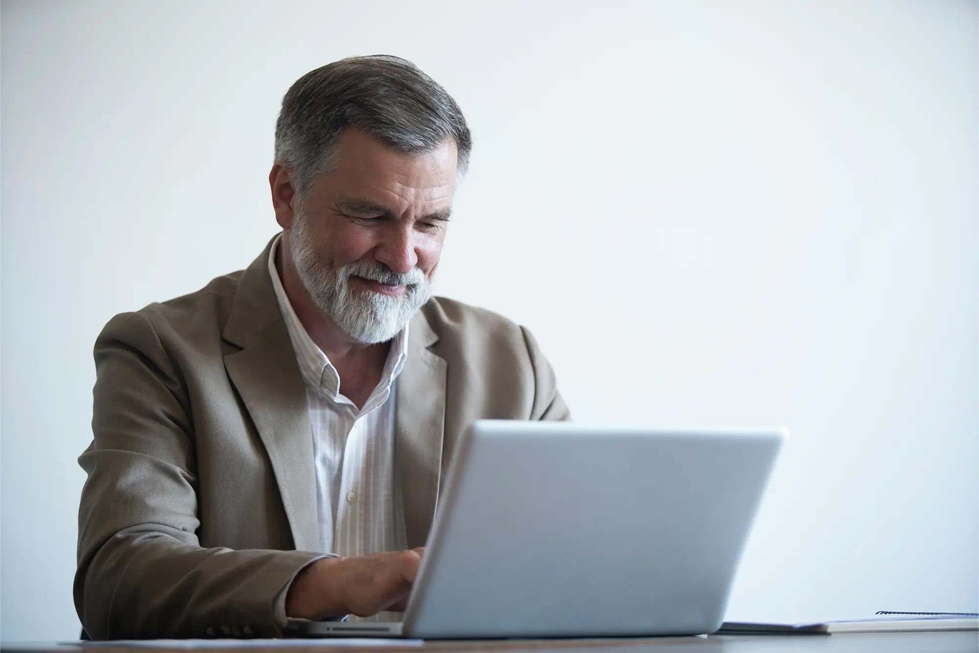 Male real estate educator working on a laptop at a desk.