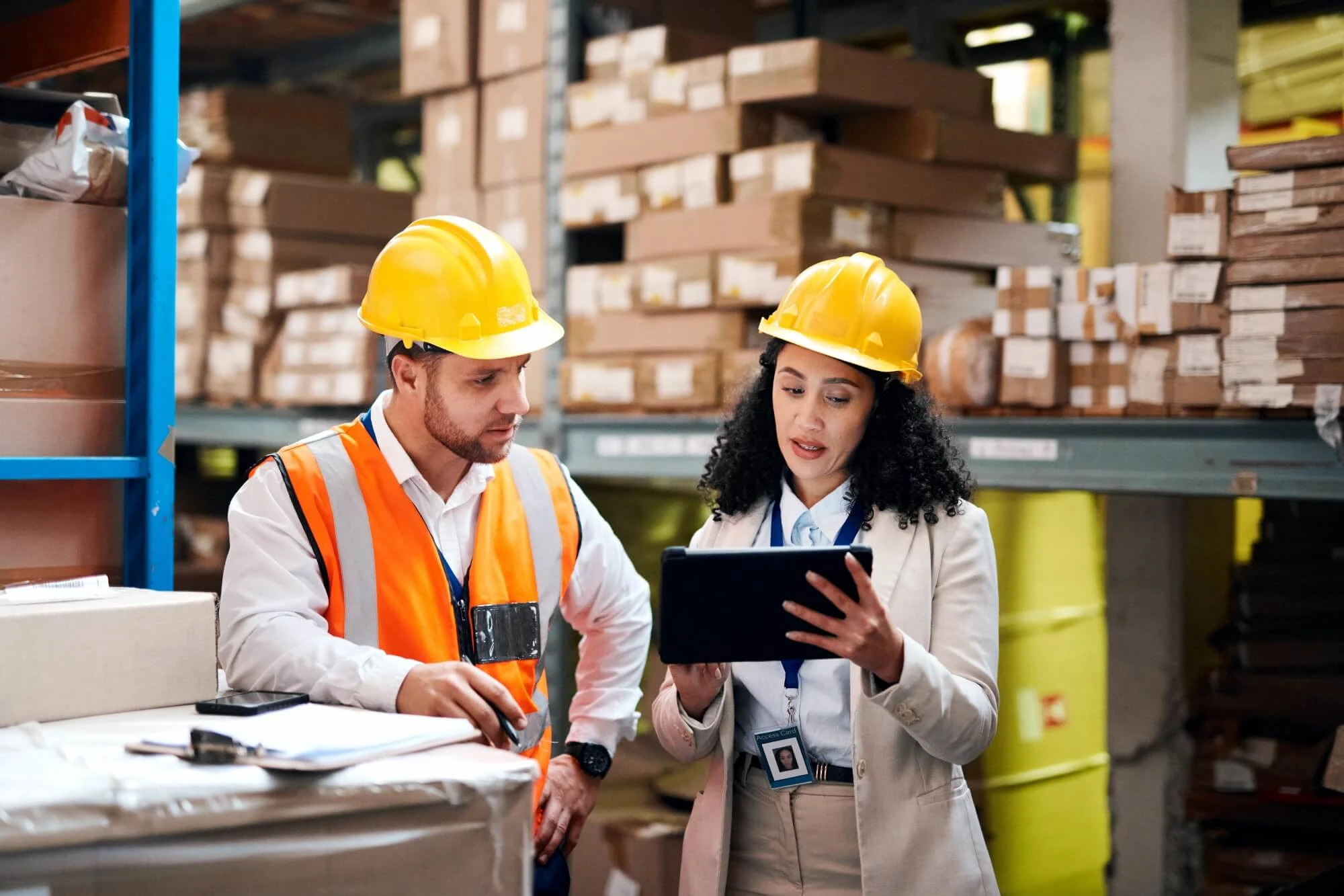 man and woman in a warehouse wearing safety hat and vest