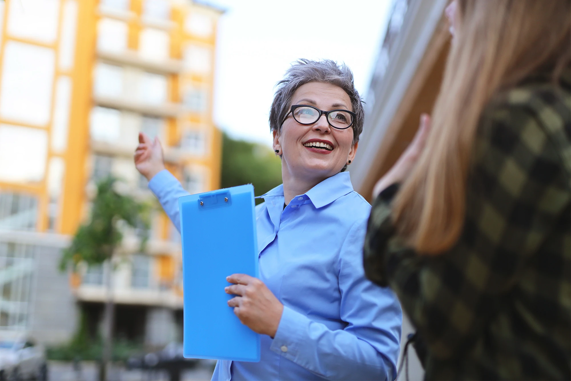 Female real estate professional showing a building to a client, providing insights into property details.