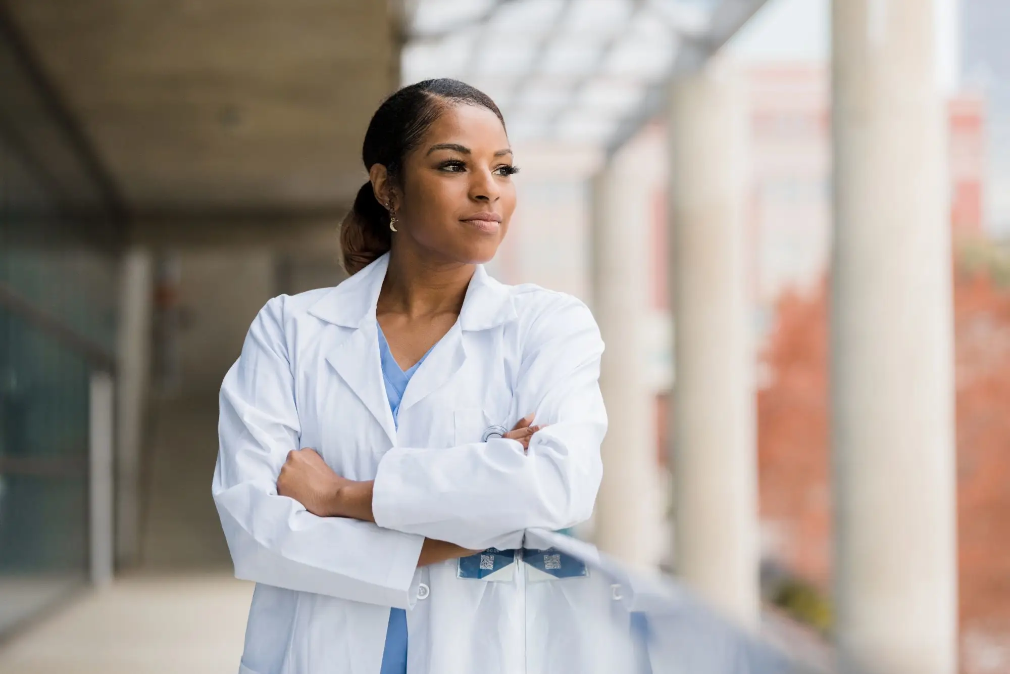 medical woman with folded arms looking outside