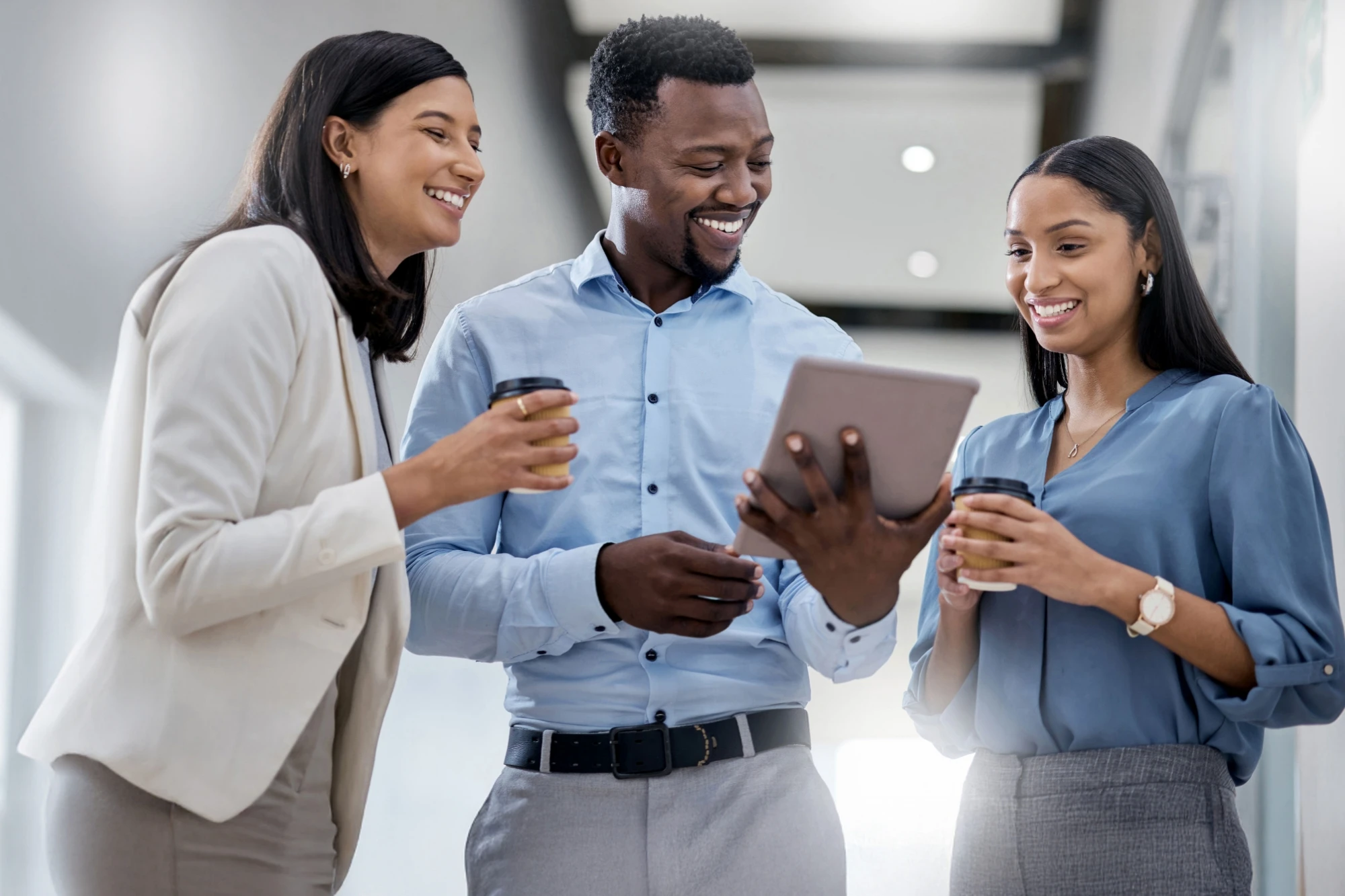 Work colleagues in an office space, smiling and looking at an item on a tablet