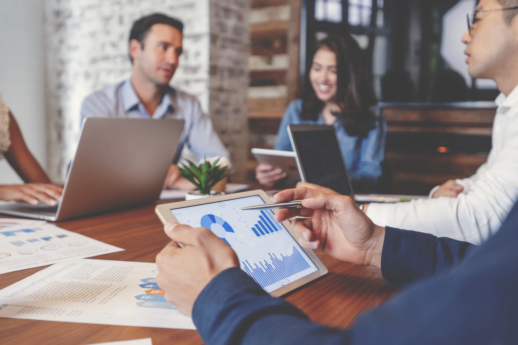 group of people in meeting looking at charts on tablet laptop