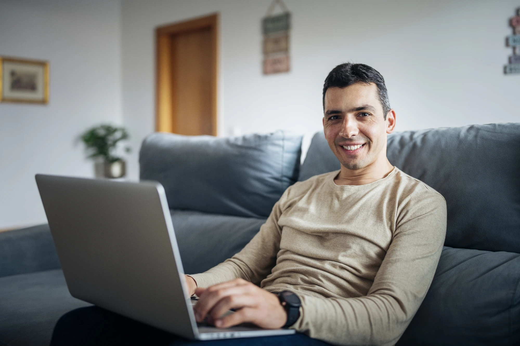 Man At Home Sitting On Sofa With Laptop