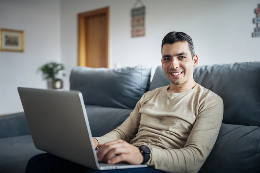 Man At Home Sitting On Sofa With Laptop