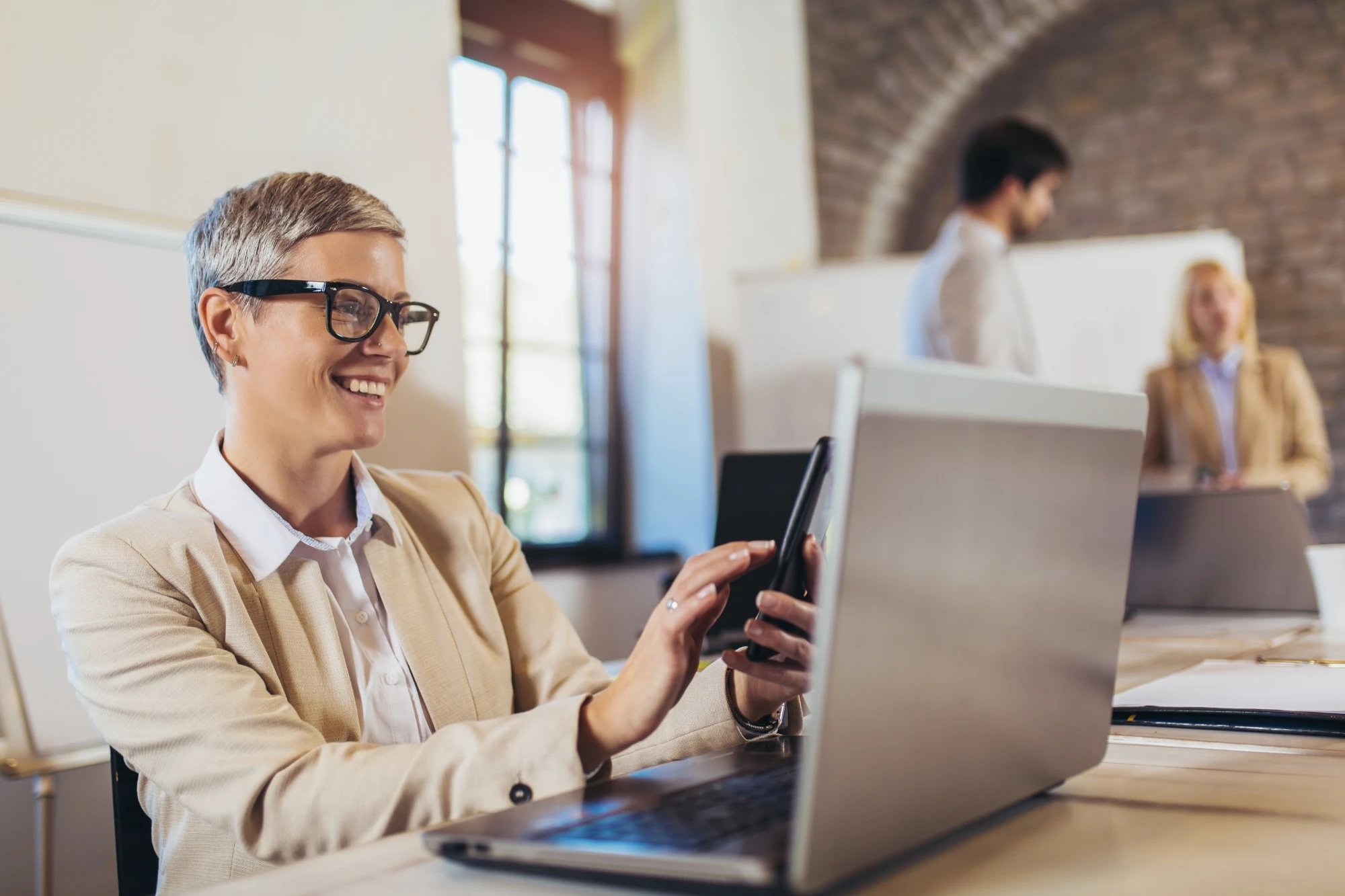woman looking at cellphone and laptop