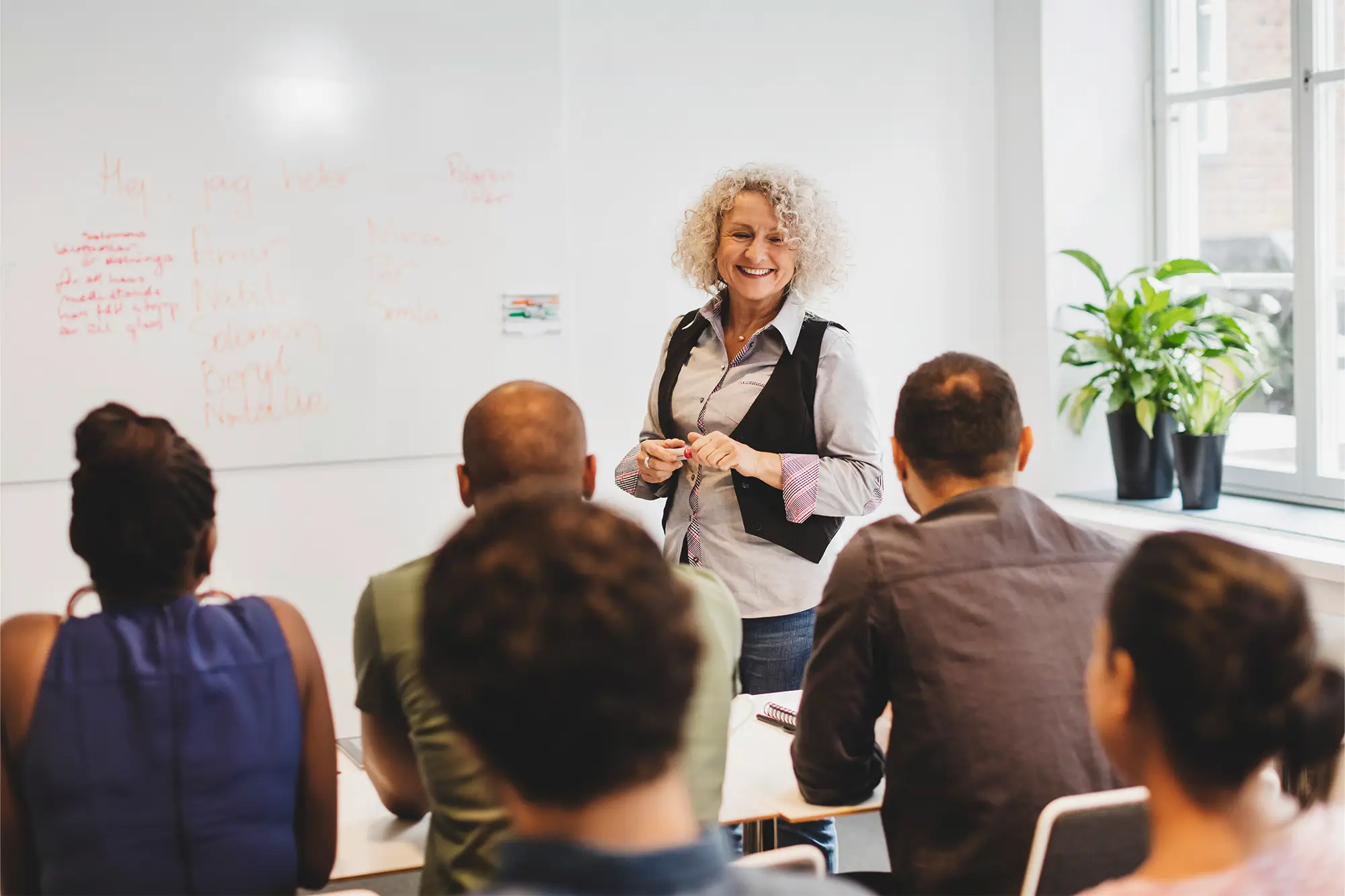 Female real estate professor teaching in a classroom, addressing students from the front of the room.