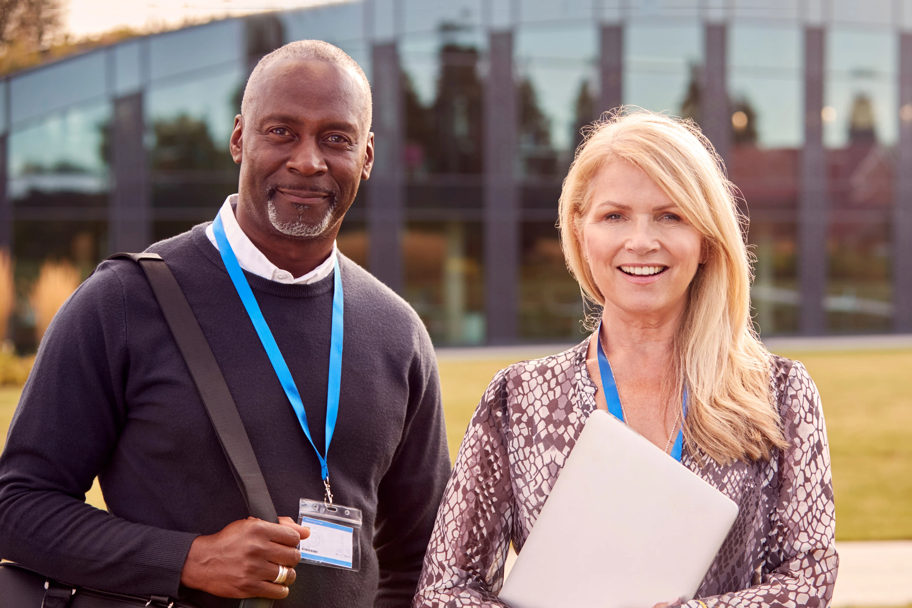 2 coworkers standing outside in front of a glass building