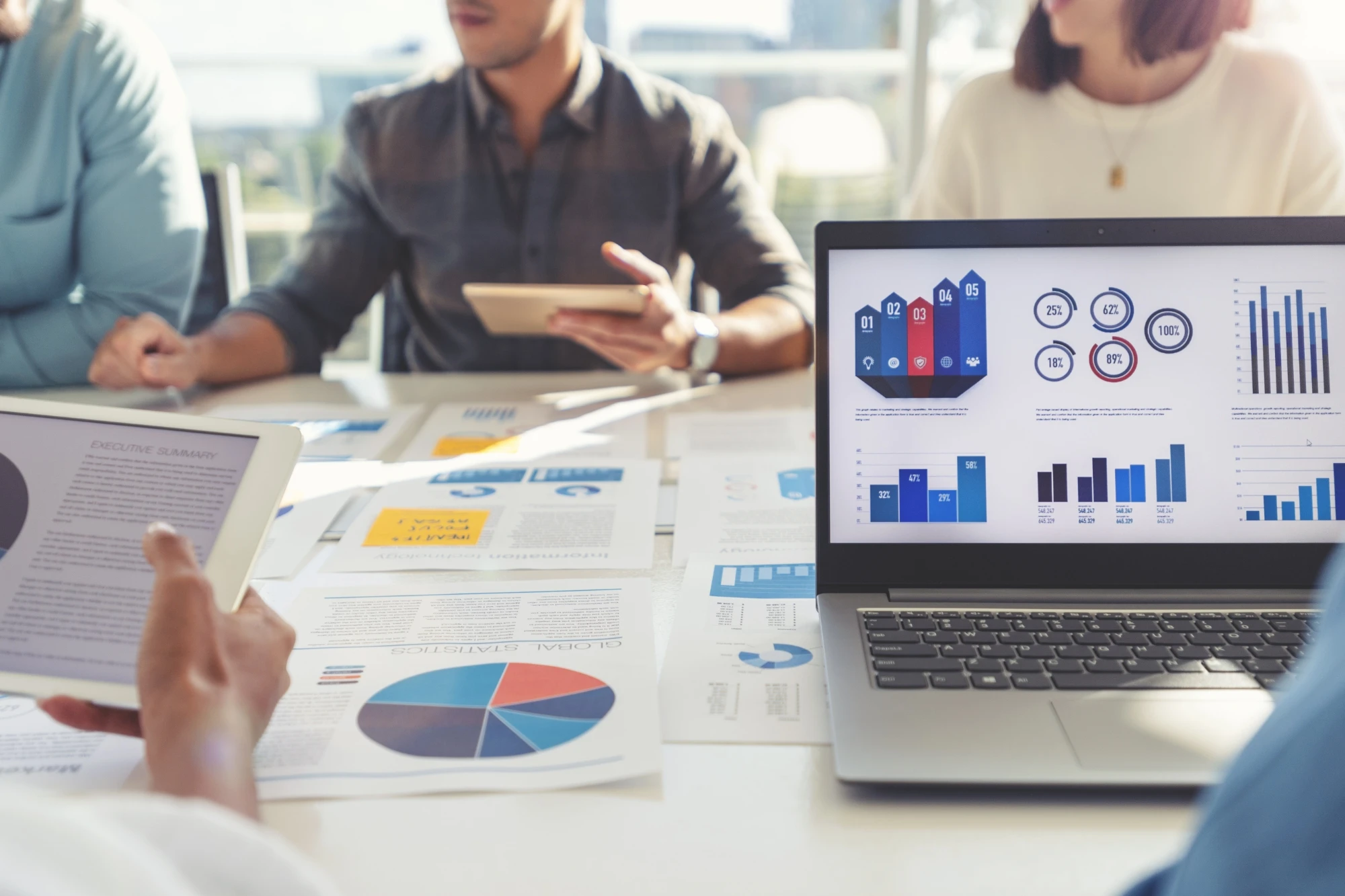 group of people in meeting looking at charts on tablet laptop
