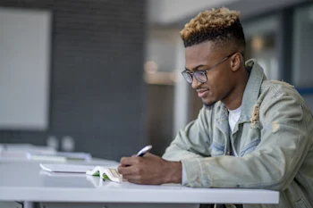 student-at-library-writing-notes-in-book