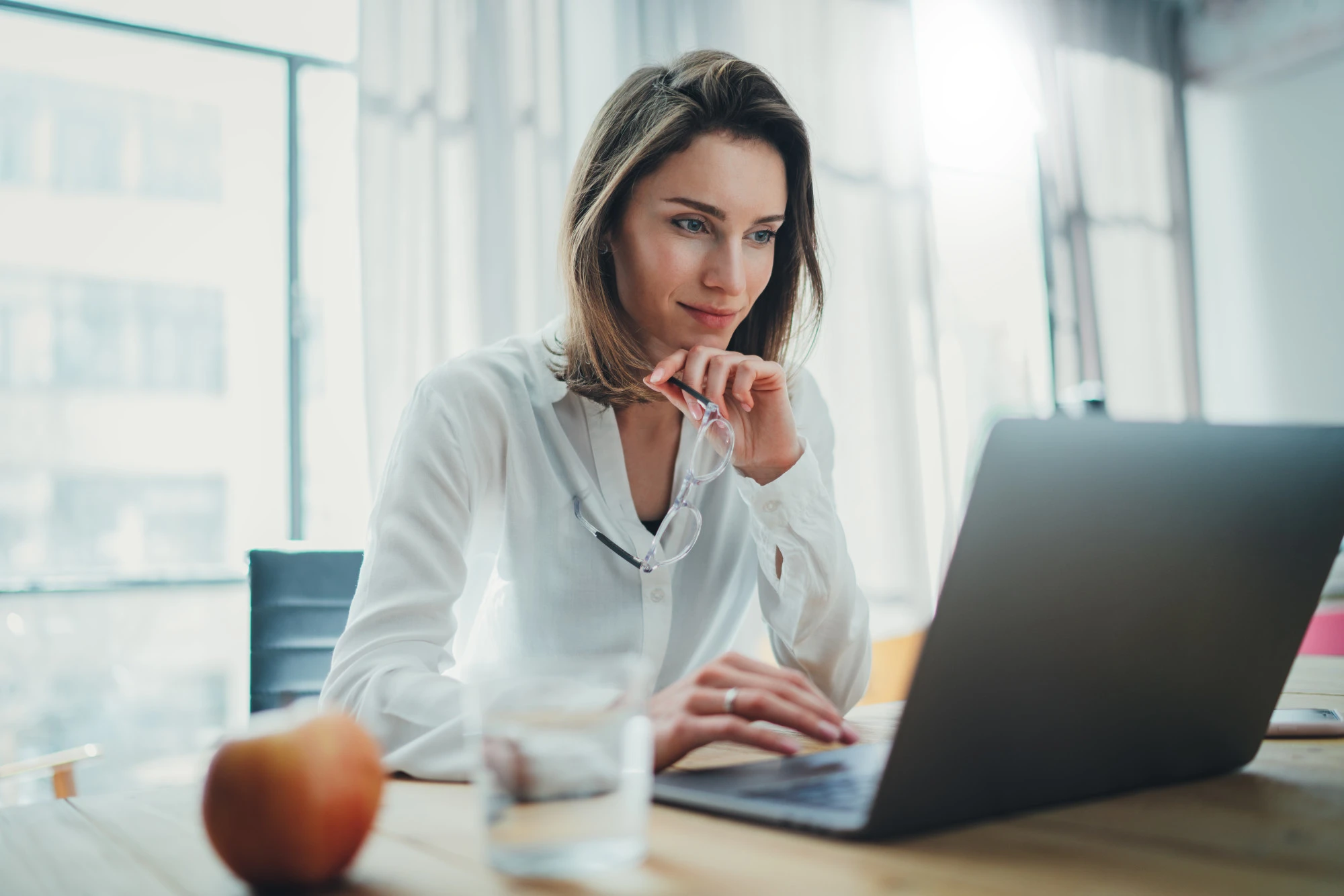 A female professional sitting at a desk in front of a laptop