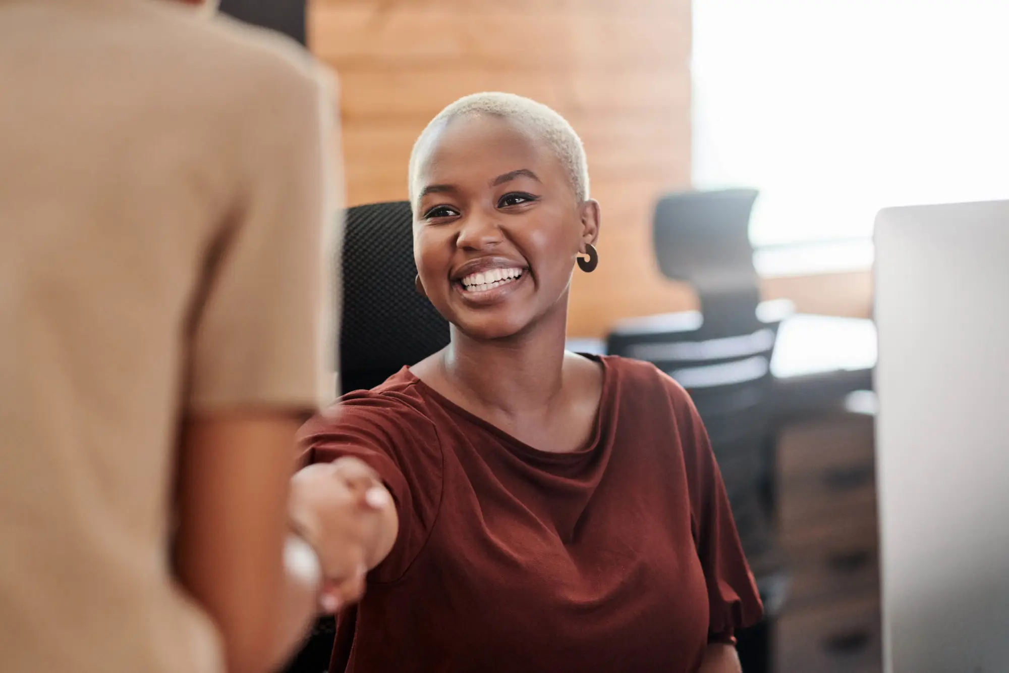 young woman in red shirt shaking hands with a colleague