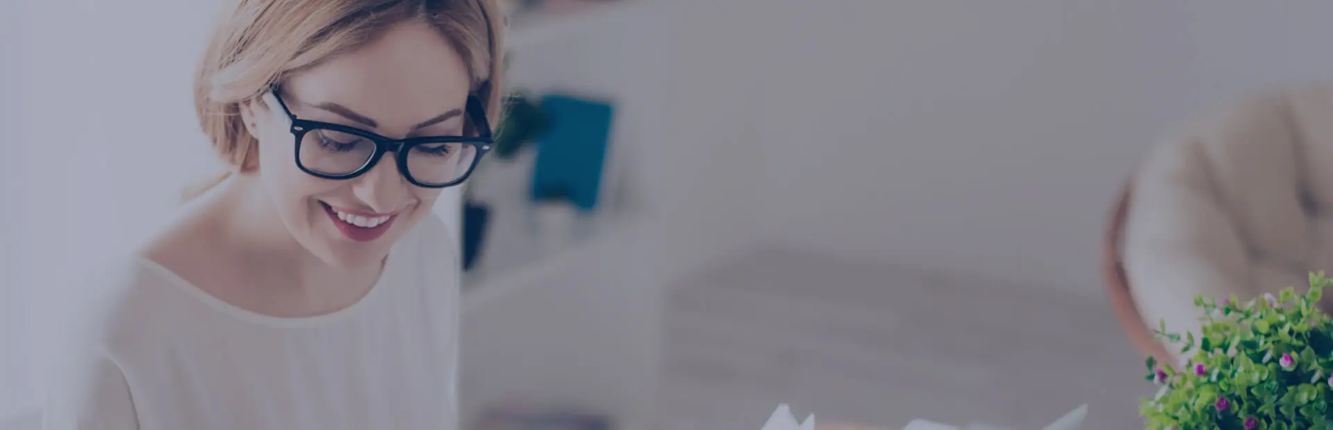 Eine etwa 30-jährige Frau mit Brille sieht in ihrem Laptop nach, wie viel Zahnersatz kostet. Sie lächelt, denn sie hat Vertrauen in blend-a-dent, egal wie sie sich entscheidet.
