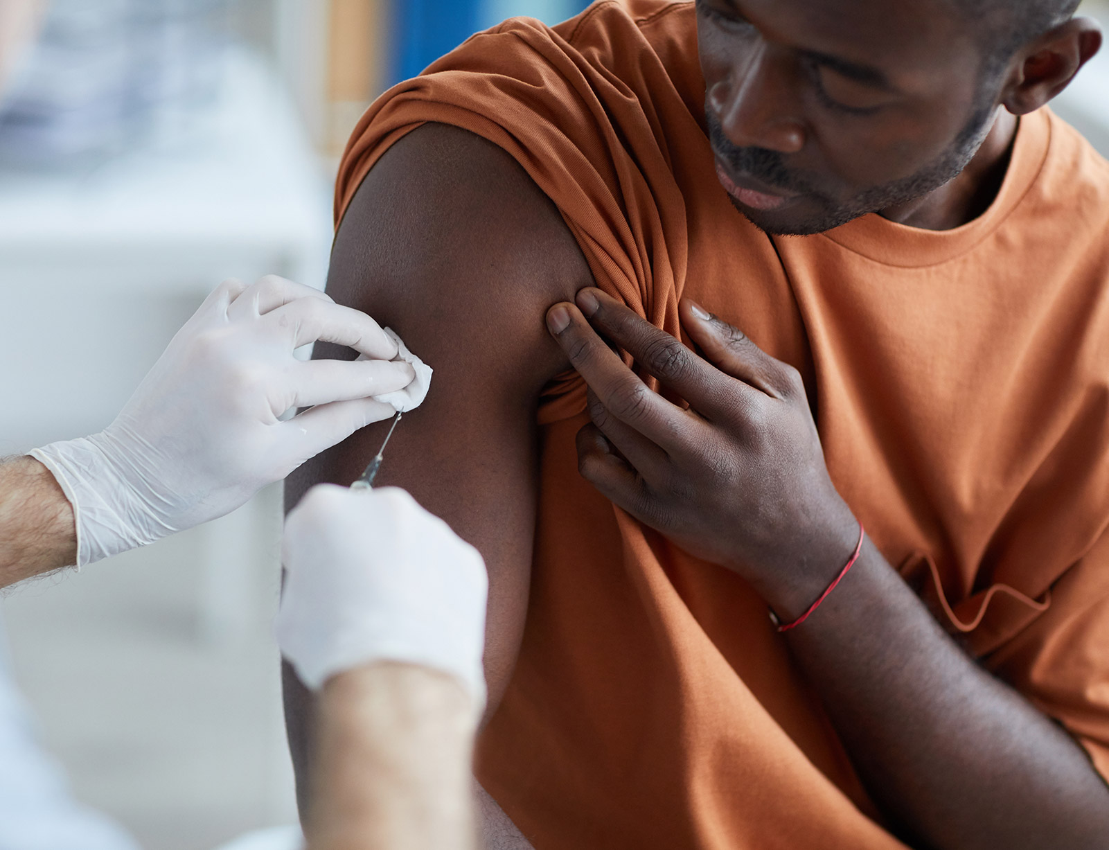 Man receiving a vaccination from a gloved medical professional