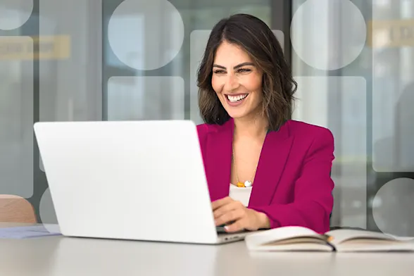 Woman in pink blazer sitting at laptop