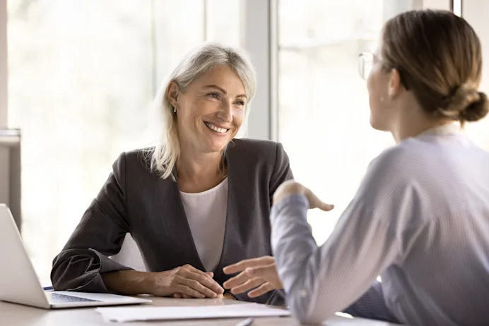 Two women talking at a desk