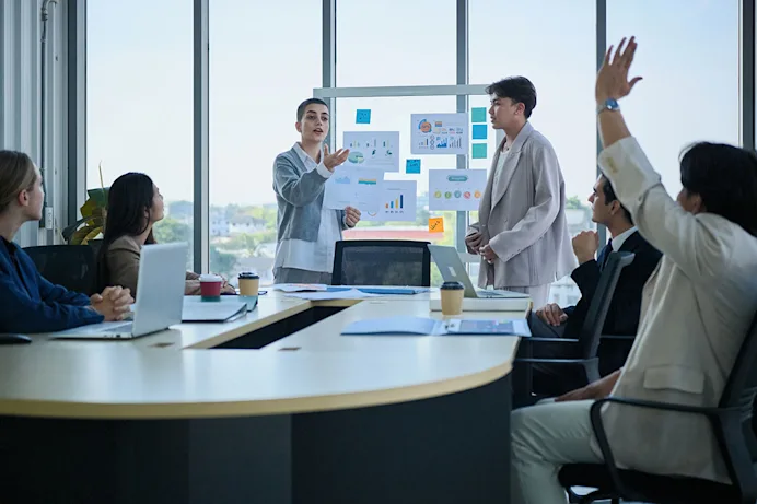 A workplace scene with businesspeople at a conference table looking at a presentation
