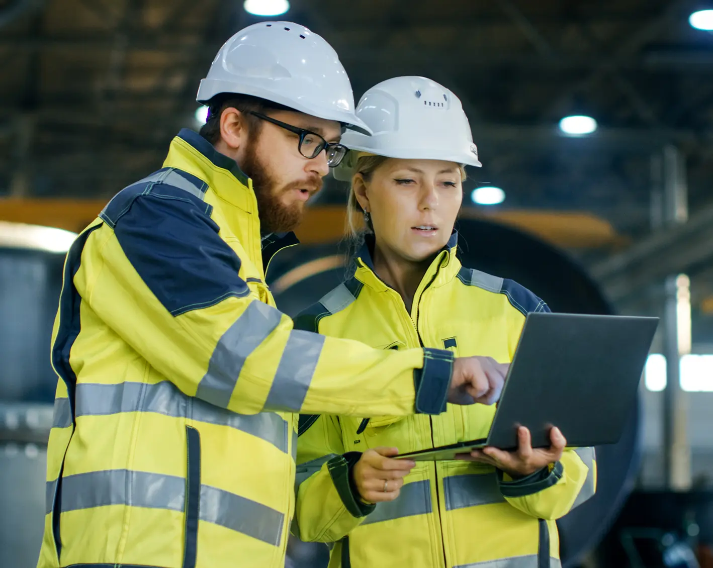 construction workers looking over engineering plans on laptop