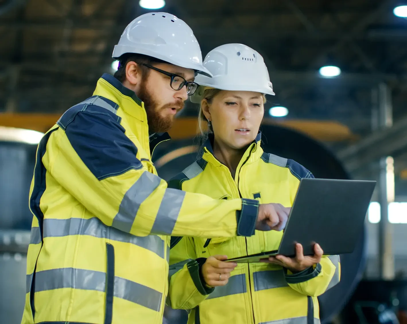 construction workers looking over engineering plans on laptop