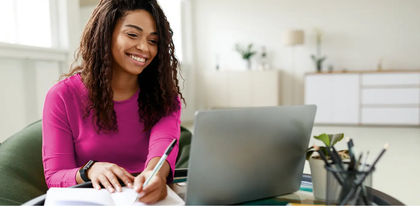 job seeker is taking notes and looking at computer