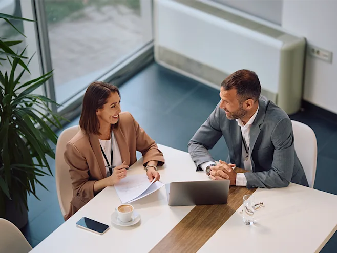 Professional, smiling woman and man sitting in conference room