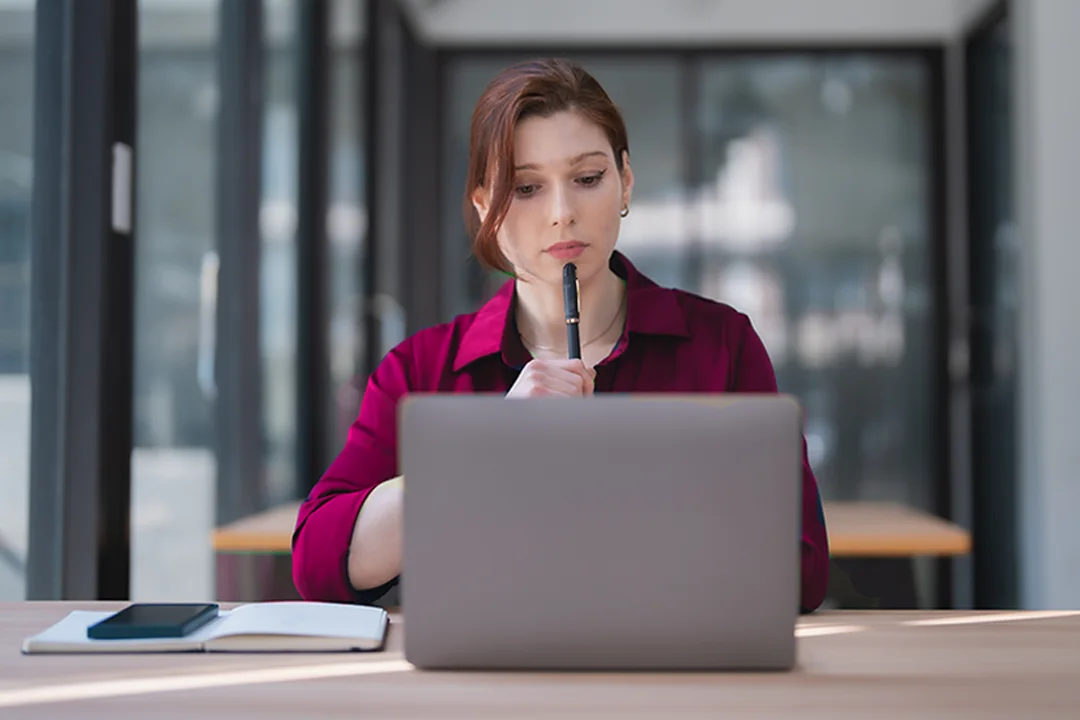 Woman in pink shirt sitting in front of a laptop