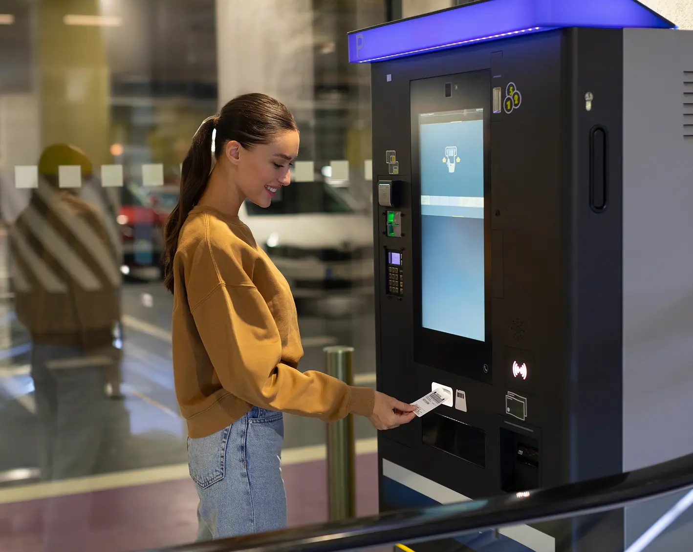 woman getting a parking pass from machine