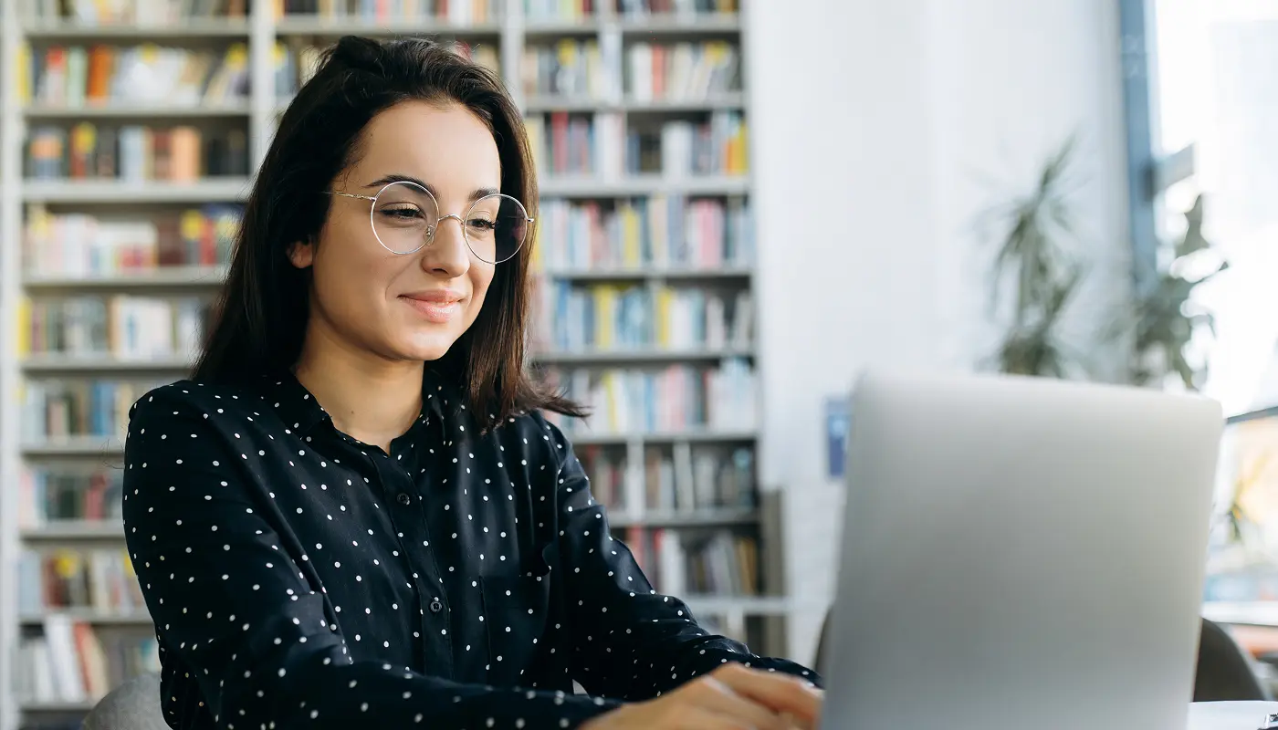 woman smiling at computer as she looks over her benefits services