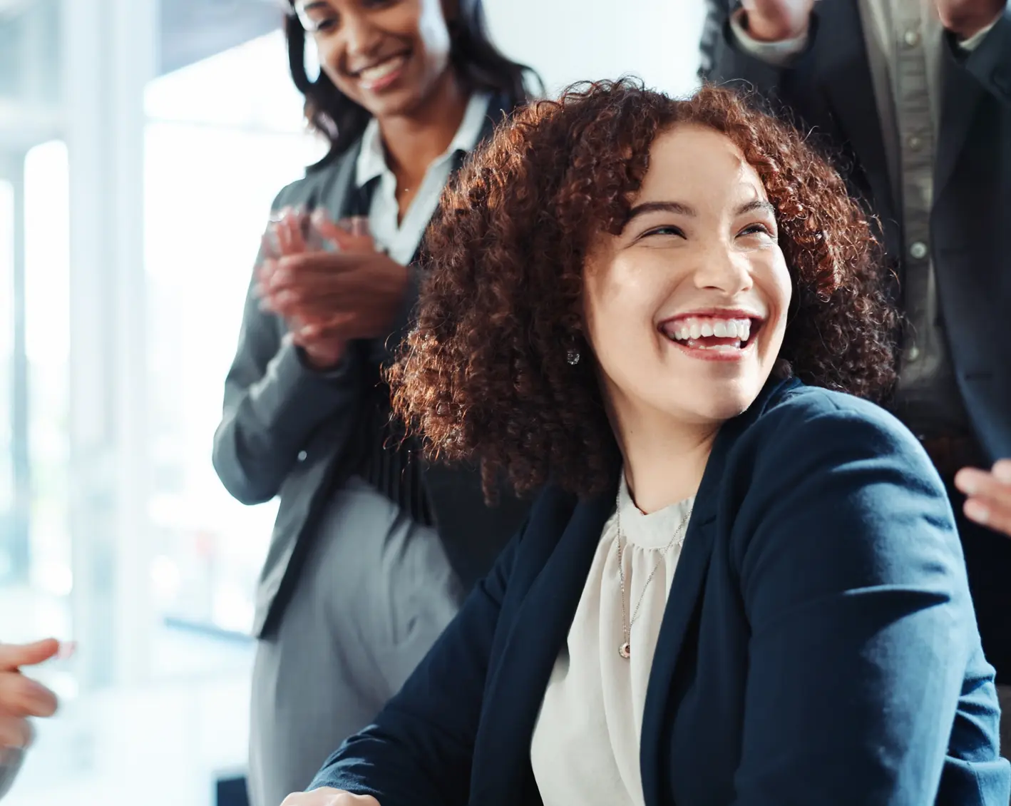 smiling woman at work with team behind her