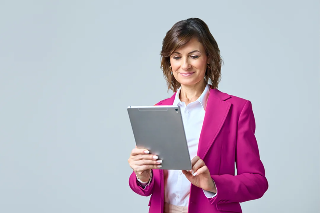 Woman in pink blazer looking at a tablet