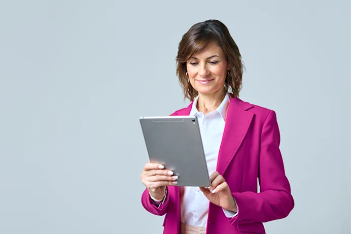Woman in pink blazer looking at a tablet