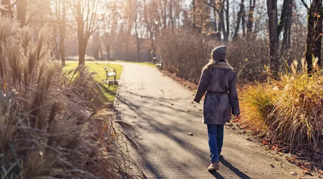Person walking on a park trail in with a jacket
