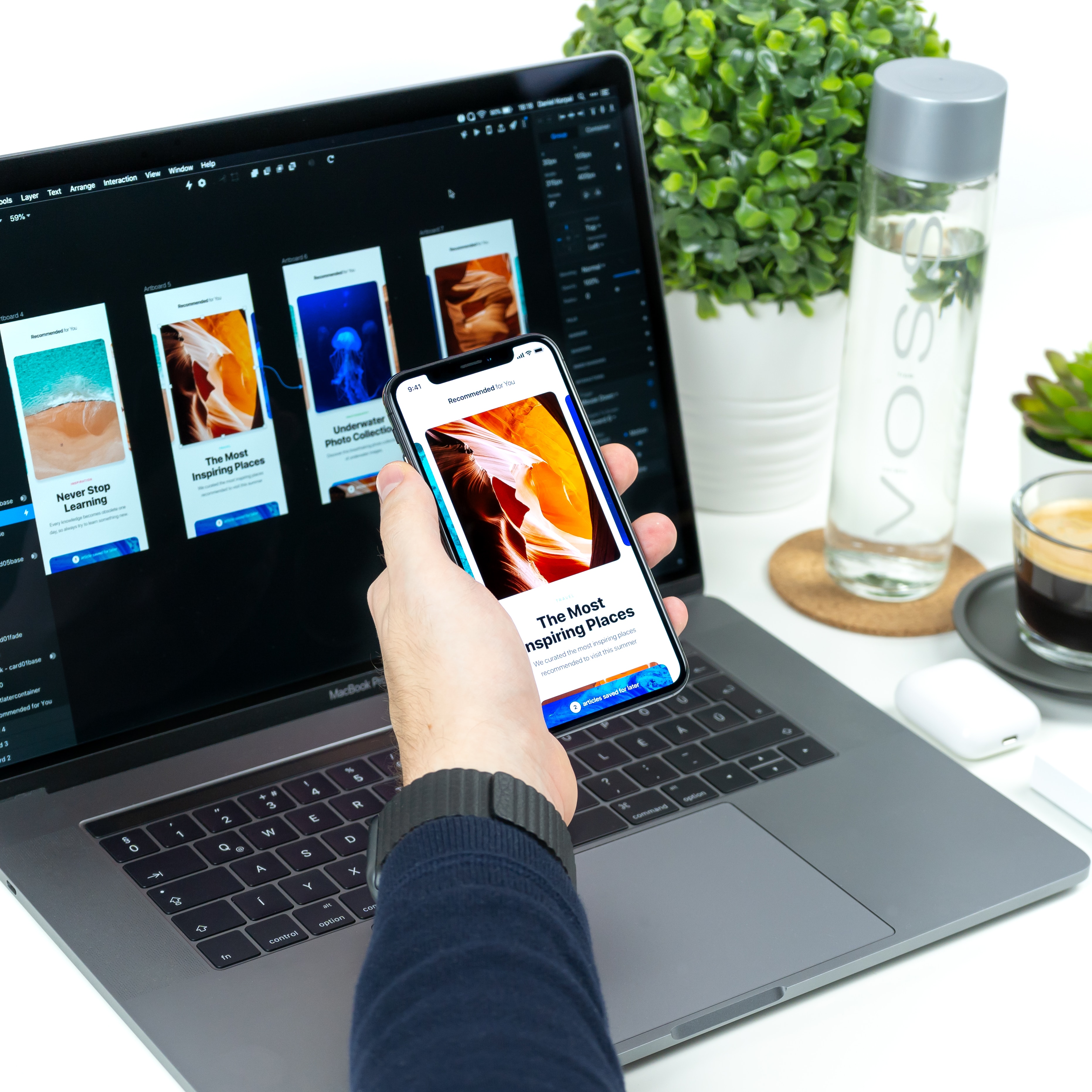App open on phone with designs open on a computer screen behind