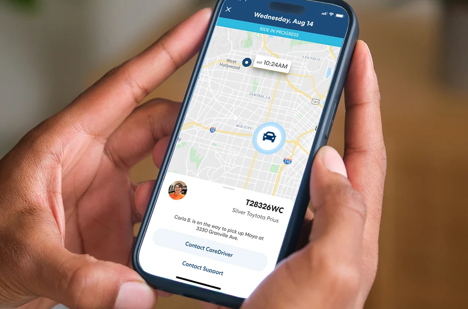 Caregiver app on a phone showing a ride in progress with a live map, vehicle T28326WC, and contact buttons