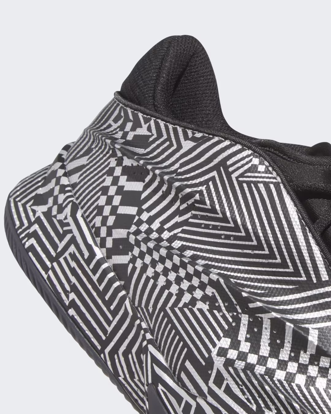 The adidas Crazy Energy+ outsole features a striking black and white geometric pattern with interlocking stripes, checkerboard designs, and optical illusions. This detailed close-up view showcases the innovative LIGHTSTRIKE Pro cushioning technology and the shoe's sculptural sole design, combining aesthetic appeal with performance-driven traction for elite basketball players.