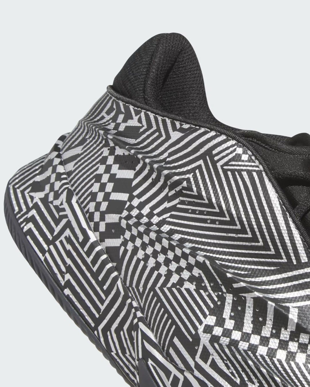 The adidas Crazy Energy+ outsole features a striking black and white geometric pattern with interlocking stripes, checkerboard designs, and optical illusions. This detailed close-up view showcases the innovative LIGHTSTRIKE Pro cushioning technology and the shoe's sculptural sole design, combining aesthetic appeal with performance-driven traction for elite basketball players.