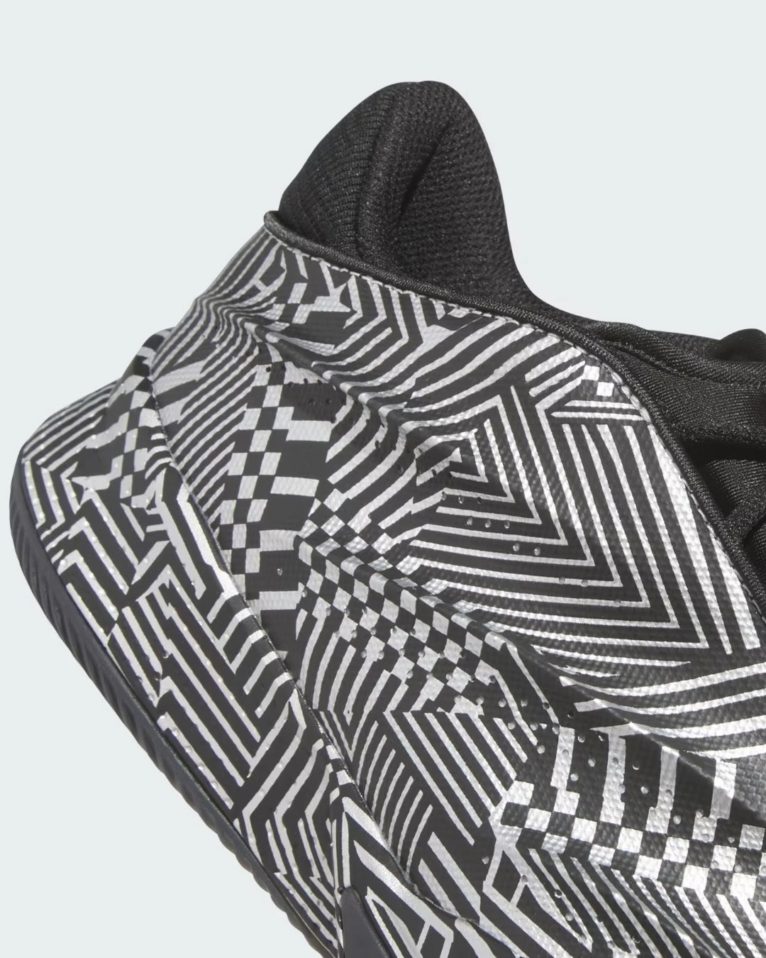 The adidas Crazy Energy+ outsole features a striking black and white geometric pattern with interlocking stripes, checkerboard designs, and optical illusions. This detailed close-up view showcases the innovative LIGHTSTRIKE Pro cushioning technology and the shoe's sculptural sole design, combining aesthetic appeal with performance-driven traction for elite basketball players.