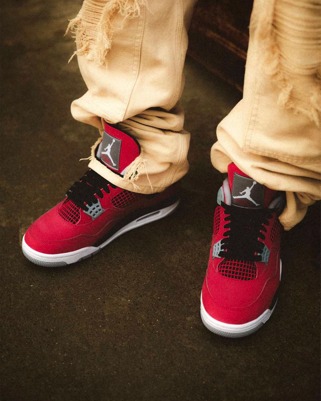 Air Jordan 4 Retro 'Toro Bravo' basketball sneakers on feet styled with beige pants