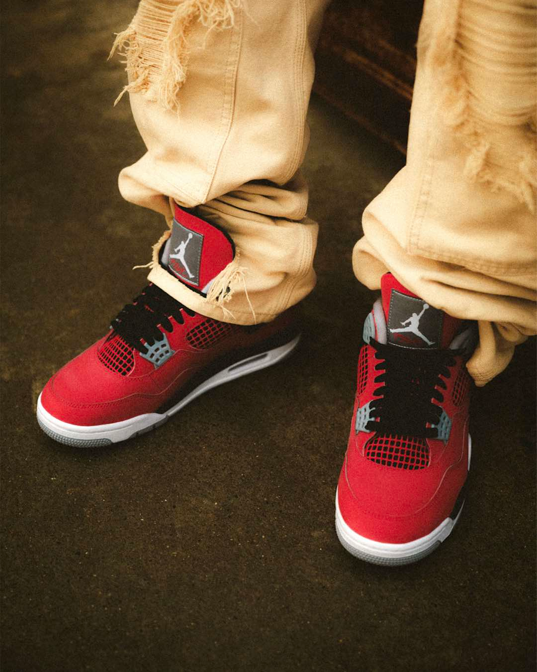 Air Jordan 4 Retro 'Toro Bravo' basketball sneakers on feet styled with beige pants