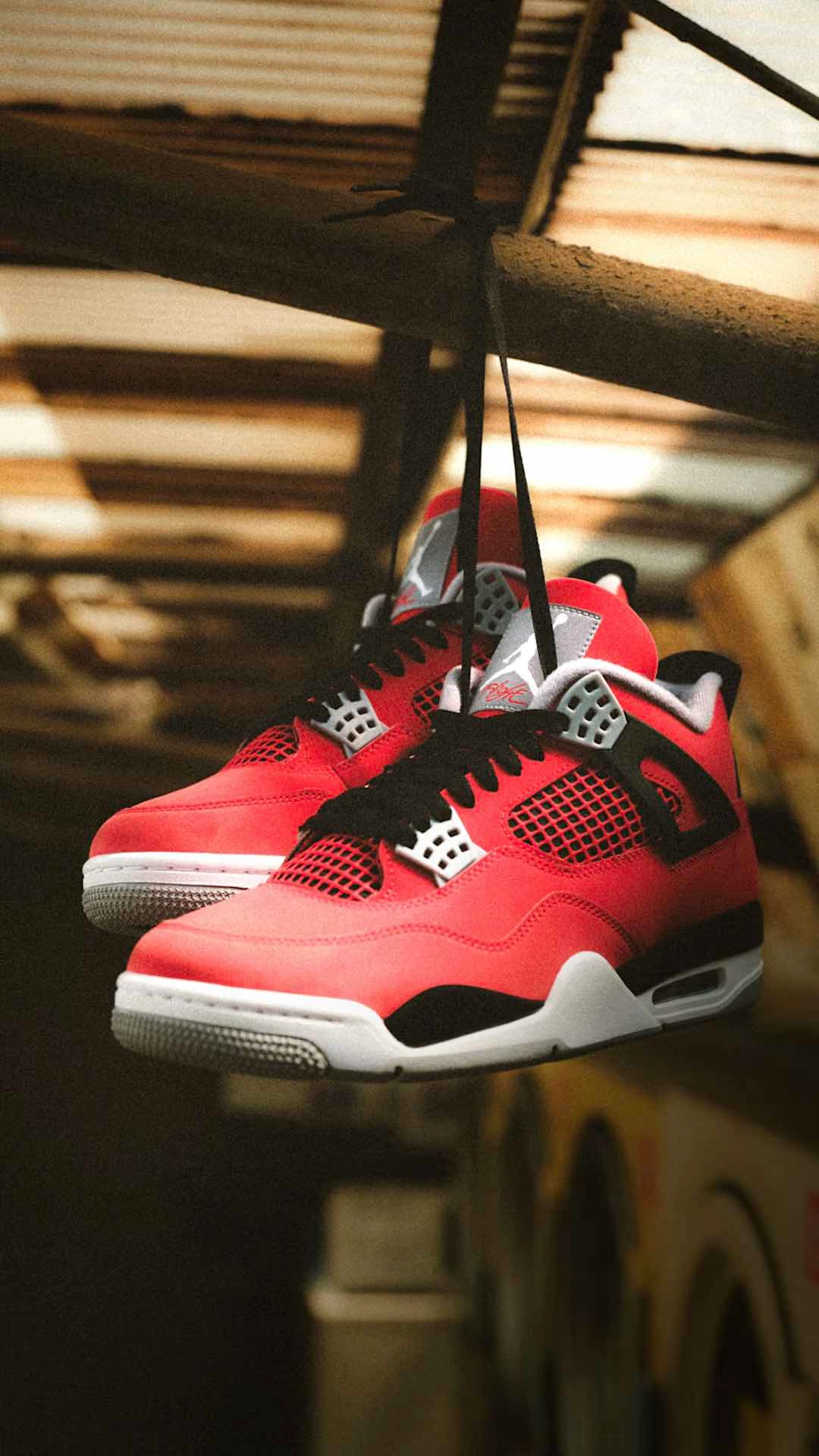 Air Jordan 4 Retro 'Toro Bravo' basketball sneakers hanging by laces in urban setting