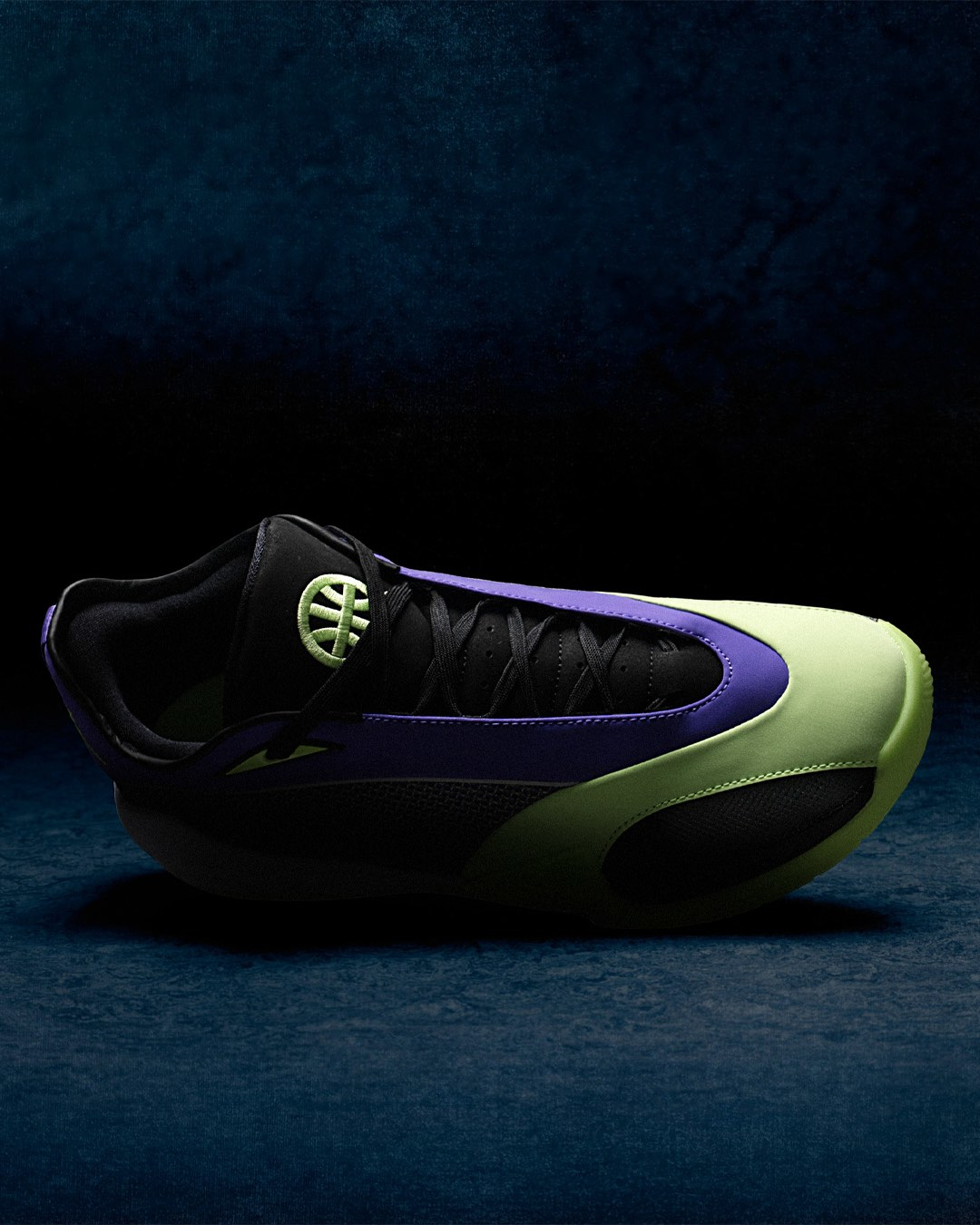 Top-down side profile of a single Jordan Triangle Q54 basketball shoe against a dark blue background. The view emphasises the shoe's low-cut silhouette and streamlined shape. The black mesh and suede upper runs the full length of the shoe, with a deep purple overlay sweeping from the heel through the midfoot. The volt green midsole curves dramatically from toe to heel, contrasting sharply against the black rubber outsole. A volt green embroidered Quai54 basketball logo is visible on the black tongue near the collar.