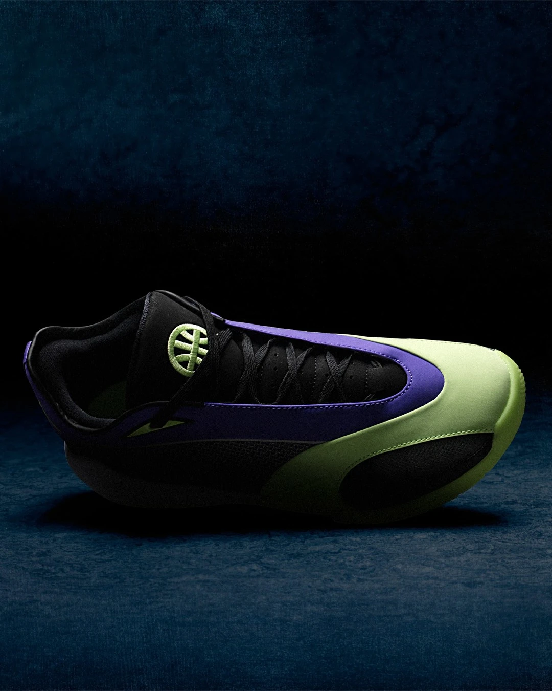 Top-down side profile of a single Jordan Triangle Q54 basketball shoe against a dark blue background. The view emphasises the shoe's low-cut silhouette and streamlined shape. The black mesh and suede upper runs the full length of the shoe, with a deep purple overlay sweeping from the heel through the midfoot. The volt green midsole curves dramatically from toe to heel, contrasting sharply against the black rubber outsole. A volt green embroidered Quai54 basketball logo is visible on the black tongue near the collar.