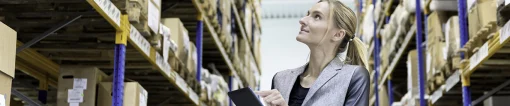 Woman with tablet checking stock in warehouse.