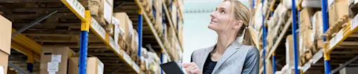 Woman with tablet checking stock in warehouse.