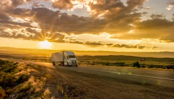 Truck driving down a scenic highway at sunset