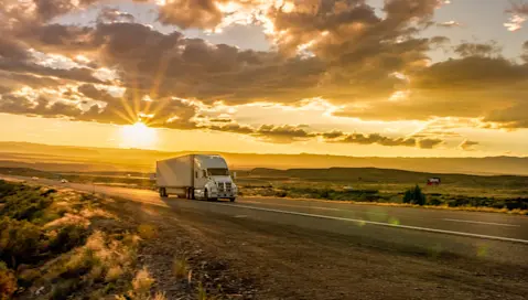Truck driving down a scenic highway at sunset