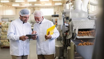 Two food facility workers review information on a tablet.